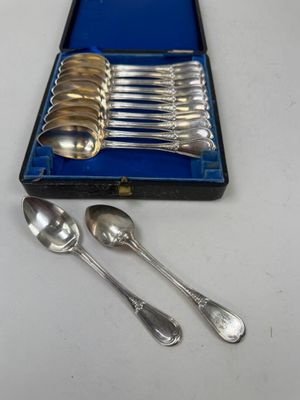 des couverts dans un coffret bleu, avec des cuillères posées sur une table