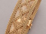 a gold bracelet with a woven design on it