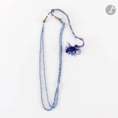 un collier de perles bleues orné d'un pompon, sur fond blanc