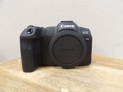 the camera is sitting on a wooden table with a white wall in the background
