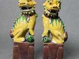 pair of yellow and green foo foo figurines sitting on top of a wooden box