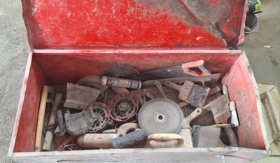 une boîte à outils rouge remplie d'outils, posée par terre