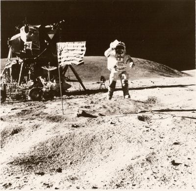photographie en noir et blanc d'un astronaute sur la Lune, à côté d'un panneau