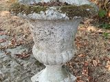 un vase en pierre recouvert de mousse, posé à même le sol