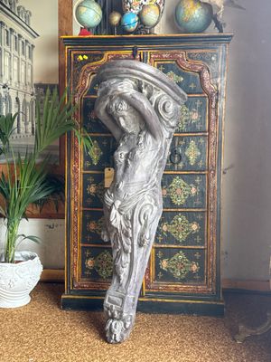 a statue of a woman holding a hat on top of a chest of drawers