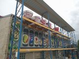 many buckets of paint on a rack outside of a building