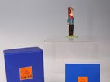 une petite figurine posée sur une boîte bleue