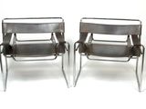 pair of chrome steel and leather chairs with arm rests on a white background
