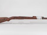 a rifle with a wooden barrel on a clear stand