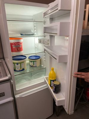 a person pointing at the inside of an open refrigerator