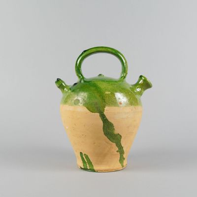a green and yellow vase with a handle on it