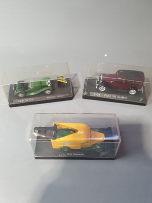 three toy cars in a clear box on a table