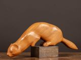 a wooden sculpture of a cat on a block on a table