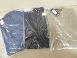 three pairs of shirts wrapped in plastic bags on a couch
