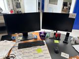 two computer monitors sitting on a desk next to each other