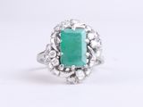 an emerald and diamond ring on a white background