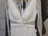 a white wedding dress hanging on a hanger in front of a brick wall