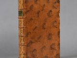 an old book with a brown cover sitting on top of a table