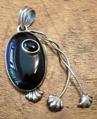 a pendant that has a black stone in it on a wooden table