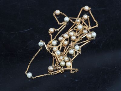 Collier plaqué or avec des perles et des chaînes sur un fond noir