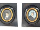 deux portraits encadrés représentant un homme et une femme, dans des cadres noirs et dorés