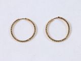two small gold hoop earrings on a white surface