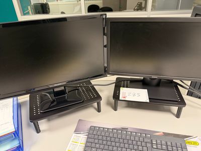 a desk with two monitors and a keyboard on it