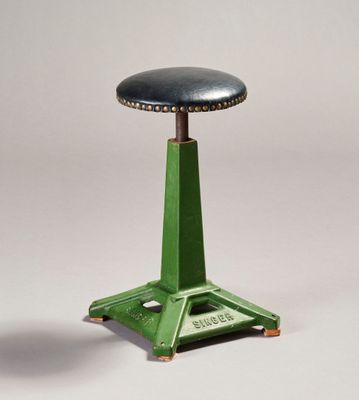 une image représentant un tabouret vert avec une assise en cuir noir