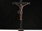 a bronze statue of jesus on the cross with a black background