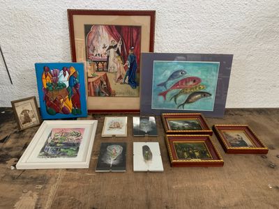 un ensemble d'œuvres d'art, encadrées et non encadrées, posées sur une table