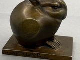 une sculpture en bronze représentant un lapin assis sur une pomme