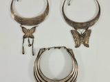 trois bijoux en argent posés sur une surface blanche