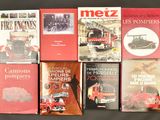 plusieurs livres posés sur une table noire, avec un camion de pompiers rouge en arrière-plan