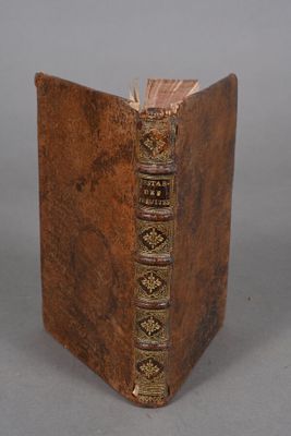 an old book with a brown cover sitting on top of a table