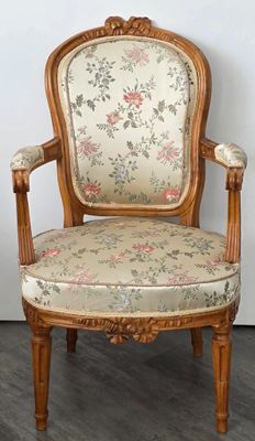 une image d'une chaise en bois dont l'assise est recouverte d'un rembourrage floral