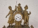 a bronze clock with three people on it