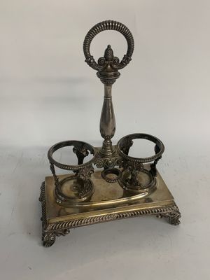 an antique silver plate with a candle holder and two cups on it
