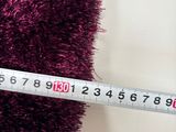 a measuring tape that is next to a pile of purple rugs
