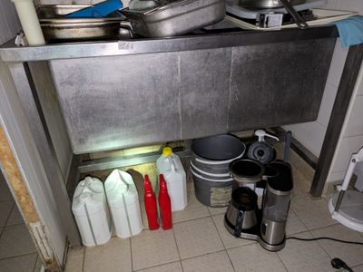 des casseroles et des poêles sont alignées par terre dans une cuisine