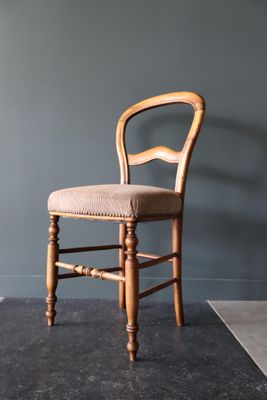 une photo d'une chaise en bois devant un mur gris