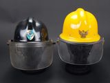 pair of yellow and black hard hats with face shields on a black background