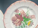 three plates with flowers painted on them sitting on a table