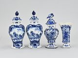 several blue and white vases and lids are lined up on a white surface