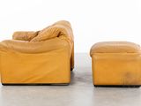 pair of yellow leather lounge chairs and ottoman on concrete floor