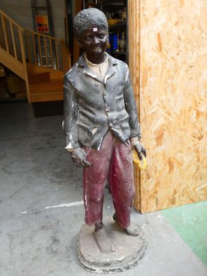 une statue représentant un garçon tenant une banane à la main