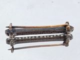 a silver and gold hair clip on a white surface