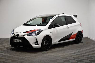 La Toyota Yaris blanche est garée dans une pièce dont le sol est à carreaux.