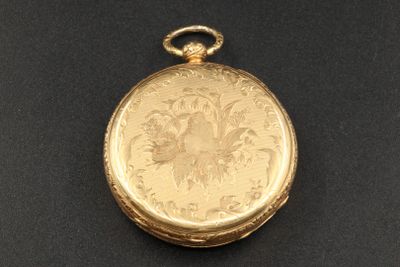 une image représentant une montre de poche en or posée sur une surface noire