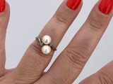 a woman ' s hand with a red manicure and a pearl ring
