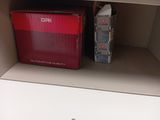 une boîte rouge posée sur une étagère, à côté d'une autre boîte